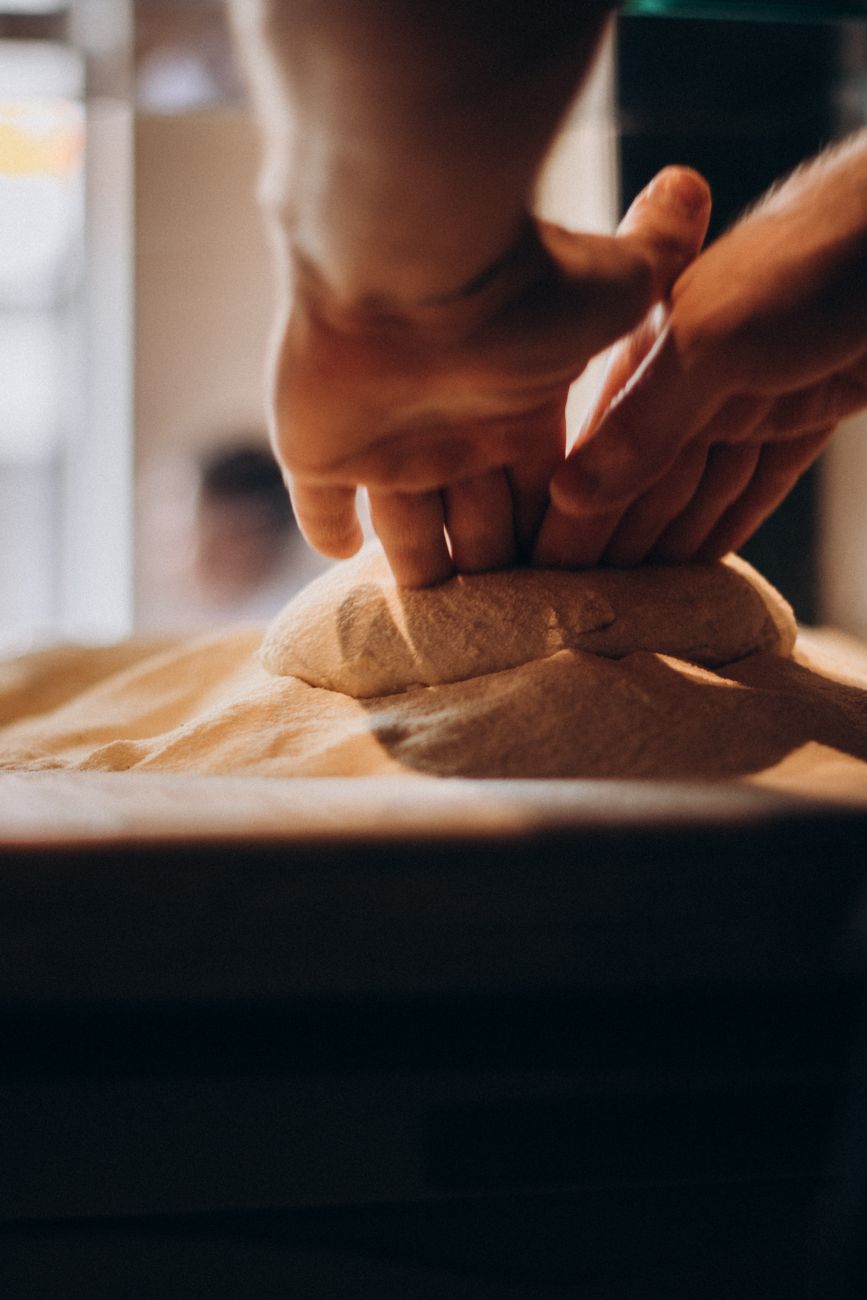 A baker working dough by hand on a floured bench
