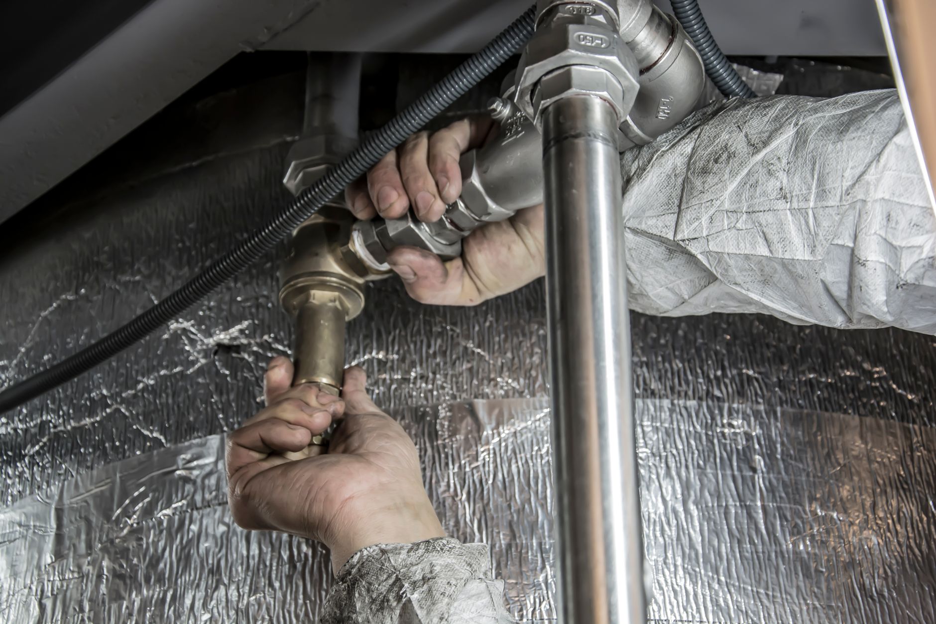 A plumber's hands working on a pipe fitting